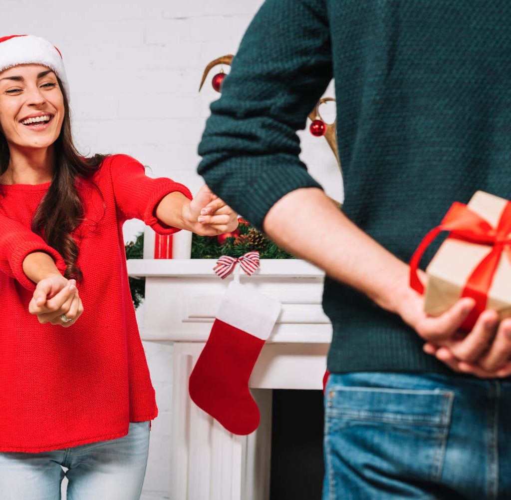 Mujer esperando regalo de navidad que esconde su novio