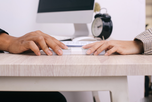 Vista horizontal de manos pasando dinero para préstamo de emergencia