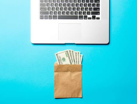 Sobre de dinero y computador portátil sobre fondo azul